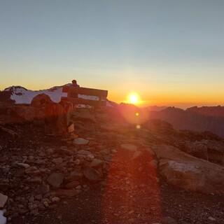 Eine Person genießt den Sonnenuntergang vom Berg aus, Foto: Julian Kasper